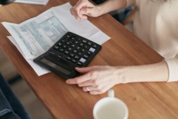 Calculator and piece of paper sitting on top of a wooden desk